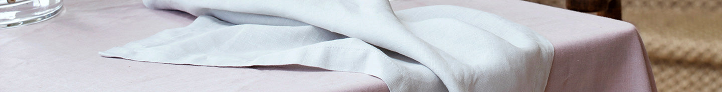 A close up on the Linen Table Napkin in Olive styled on a Linen Tablecloth in Natural.