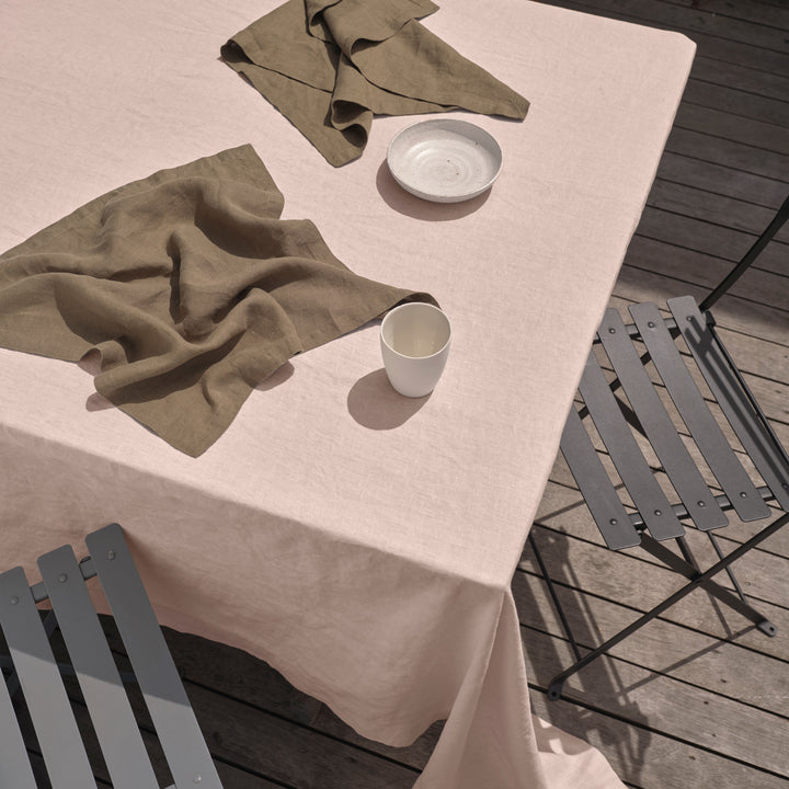 An outdoor table setting featuring a Linen Tablecloth in Blush, paired with Linen Napkins in Olive. Available in Small 150cm x 240cm & Medium 180cm x 300cm.