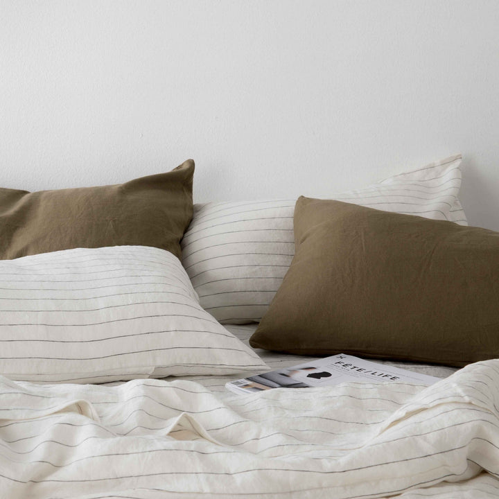  A close up of Olive and Pencil Stripe bed linen, styled with a magazine. Available in Single, Double, King, Super King.