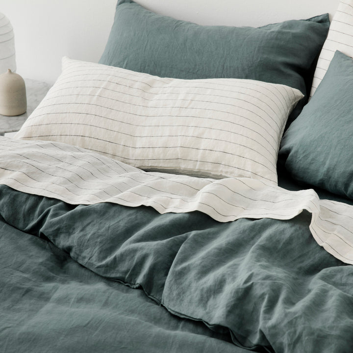 A combination of a Set of 2 Linen Pillowcases and a Flat Sheet in Pencil Stripe, and a Duvet Cover Set in Bluestone on a bed. Available in Standard & King.
