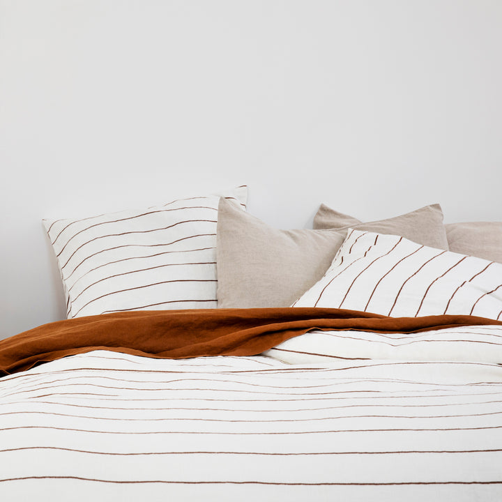A bed dressed in Cedar Stripe, Cedar and Natural bed linen. Available in Standard & King.