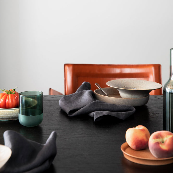 A wooden table styled with various ceramic bowls, fruits and the Linen Table Napkins in Slate