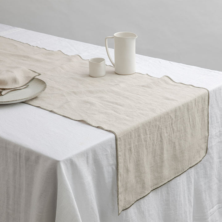 Cara Edged Table Runner in Olive on a Linen Tablecloth in White