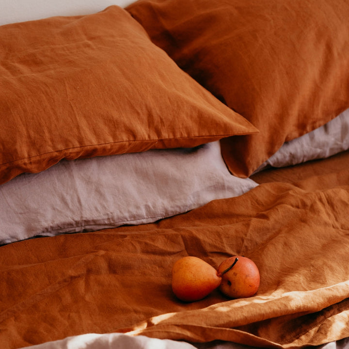 A close up of a bed dressed in Cedar and Dusk bed linen, styled with fruit. Available in Double, King, Super King.
