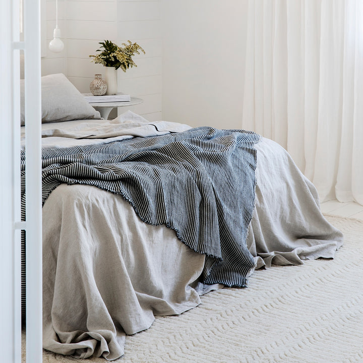 A bed dressed in Smoke Grey bed linen, styled with a Mira Linen Throw in Ellis Stripe. Available in Double, King, Super King.