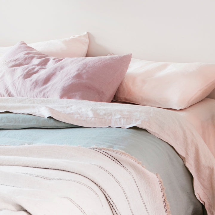 A bed dressed in Dusk, Blush and Sage bed linen, styled with a Mira Linen Throw in Ana