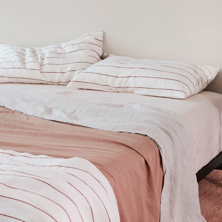 A bed dressed in Cedar Stripe, Blush, Smoke Grey and Fawn bed linen. Available in Double, King & Super King.