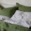 A close up of a bed styled with a Linen Duvet Cover and Set of 2 Linen Pillowcases in Forest and a Linen Sheet Set in Pinstripe.