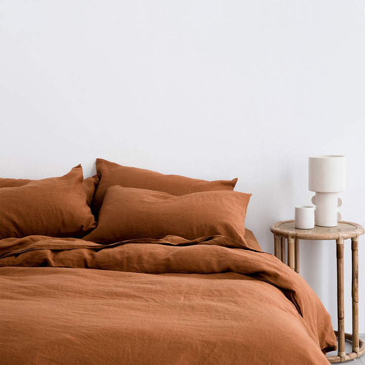 A bed dressed in Cedar bedlinen, styled with a natural side table, and white vessels. Available in Standard & King.