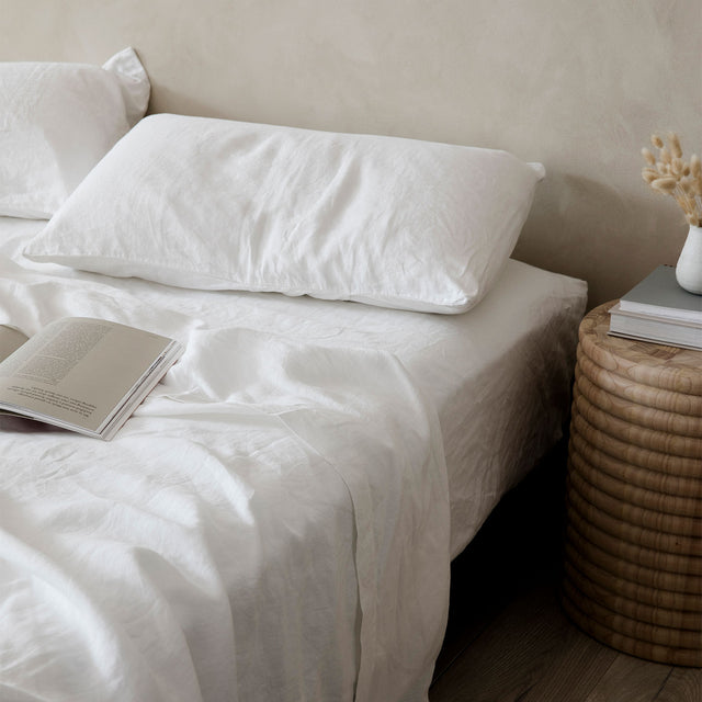 A bed dressed in White bed linen, styled with a wooden bedside table and book. Available in Double, King, Super King.