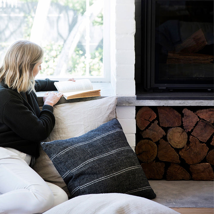 A woman sitting next to a Mira Linen Cushion Cover in Rafa