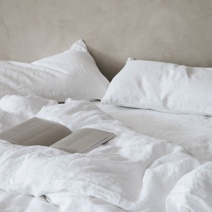 A bed dressed in White bed linen, styled with a book. Available in Single, Double, King, Super King.
